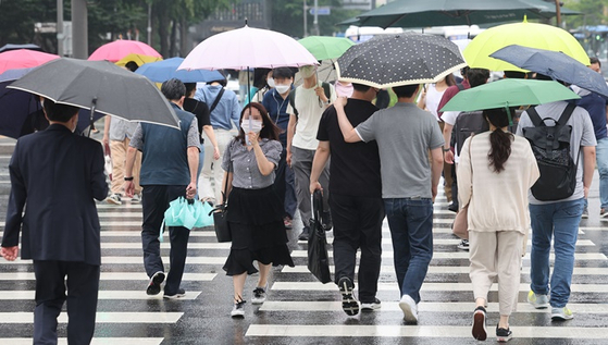 전국 곳곳에 장맛비가 내리기 시작한 지난 23일 오전 서울 광화문광장에서 시민들이 우산을 쓴 채 걸어가는 모습. 〈사진-연합뉴스〉