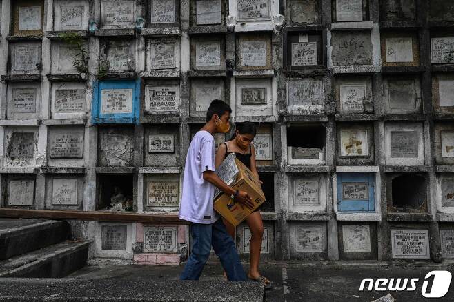 지난 10일(현지시간) 필리핀 수도 마닐라 노발리체스의 백백 묘지에서 '마약과의 전쟁' 희생자 유족들이 유해가 담긴 상자를 들고 있다. 22.06.10 © AFP=뉴스1 © News1 김예슬 기자