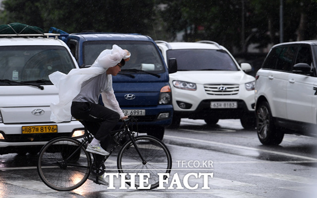비옷을 입은 한 시민이 바람을 막으며 자전거를 운행하고 있다.