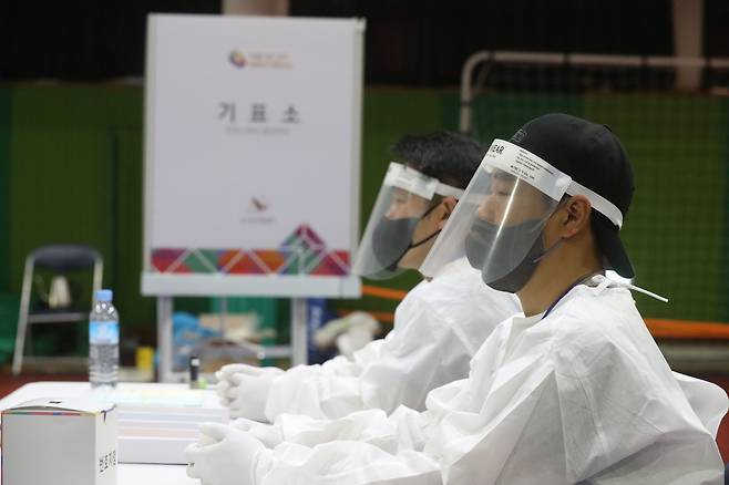 지난 1일 대전 중구 서대전초등학교 체육관에 마련된 투표소에서 투표사무원들이 코로나19 확진자 투표를 위해 방호복을 입은 채 대기하고 있다. /뉴스1