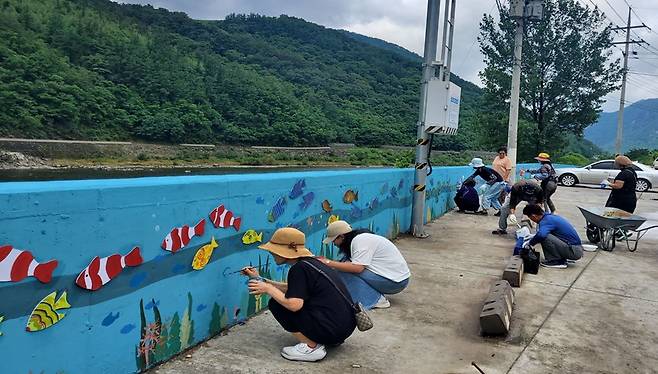 단양군 영춘면 사지원1리 주민들과 벽화봉사단이 담장에 그림을 그리고 있다. 단양군 제공