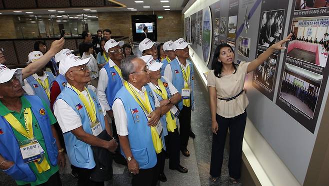 2012년 새에덴교회 초청으로 한국을 찾은 필리핀 참전용사들이 국회의사당을 방문해 당시 이자스민 의원의 설명으로 한국의 발전상을 담은 사진을 관람하고 있다. /오종찬 기자