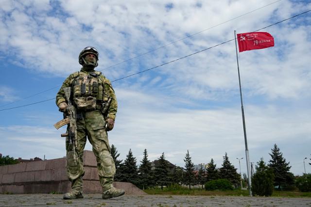 지난 5월 20일 한 러시아군이 우크라이나 남부 헤르손에 위치한 '명예의 길(Alley of Glory)'에 경비를 서고 있다. 옆에는 77주년 전승절을 기념하는 전승기가 설치돼 있다. 헤르손=AP 연합뉴스