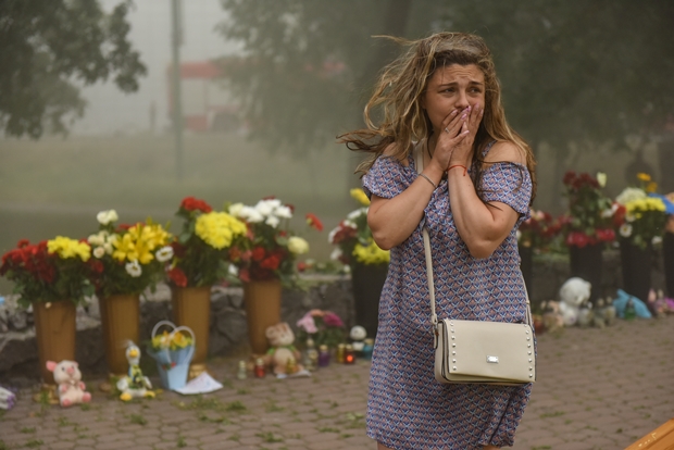 28일(현지시간) 우크라이나 폴타바주 크레멘추크시 암스토르 쇼핑몰 앞에 마련된 추모공간에서 한 여성이 눈시울을 붉히고 있다. EPA 연합뉴스