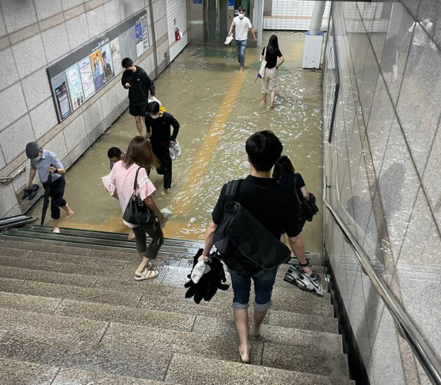 경기 수원 세류역의 지하통로가 물에 잠겨 출근길 시민들이 바지를 걷고 맨발로 이동하는 모습.(사진=사회관계망서비스 갈무리)