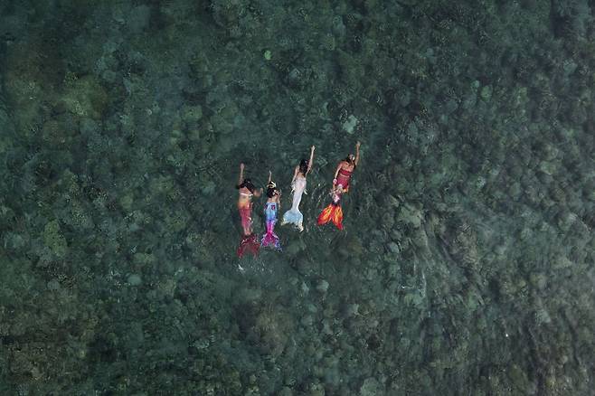 5월 22일 필리핀 바탕가스주 마비니에서 열린 인어 수업에서 세명의 수강생들이 강사 퀸 팡케 타보라(오른쪽)을 따라 수영을 하고 있다./AP 연합뉴스