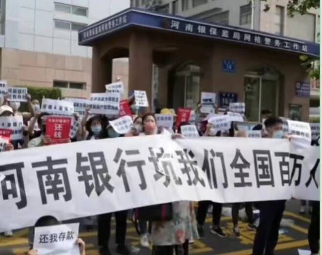 “허난은행은 전국 백만 명의 사람들에게 해를 입혔다”라는 내용이 담긴 현수막을 든 예금주들의 시위, 지난 5월 (출처:웨이보)