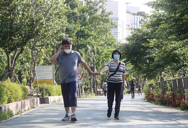 2022년 5월 27일 오후 서울 성동구의 한 도로에서 김남연(55)씨가 아들 이윤호(24)씨와 산책을 하면서 손에 수건을 잡고 있다. 수건 대신 손을 잡을 경우 땀이 생기면서 이씨가 손을 놓을 수 있다. / 장련성 기자