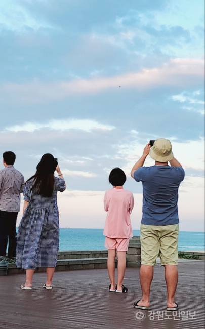 ▲ ▲지난달 28일 망상해수욕장 북쪽 끝자락에 위치한 망상오토캠핑리조트 앞 해변 데크에 마련된 ‘드론배송존’애서 디스이즈엔지니어링이 운용하는 ‘드론음식배송서비스’에 치킨 주문을 한 가족이 멀리 해안가 상공에서 하늘길을 이용해 다가오는 드론을 보며 신기하고 반가운 마음에 사진을 찍고 있다.