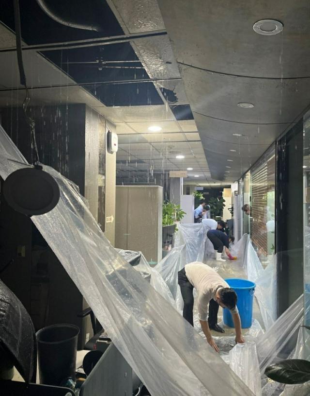 80년 만의 폭우가 쏟아졌던 8일 저녁 서울 여의도 한국투자증권 5층 사무실에 물이 새면서 직원들이 비닐로 집기를 덮고 있다. 온라인 커뮤니티 캡처