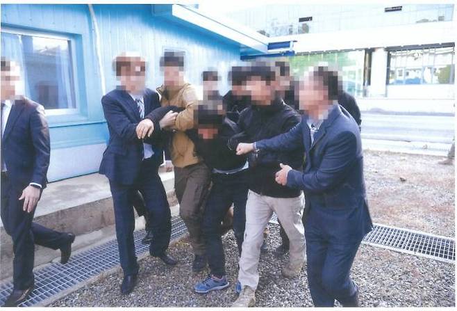 몸부림치며 버티는 탈북 어민을 남한 당국자들이 강제로 끌고 가고 있다.   통일부 제공