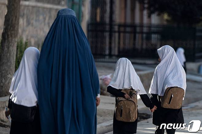 아프가니스탄 카불 거리의 모습. 부르카를 쓴 여성이 히잡을 쓰고 등교하는 딸들과 걷고 있다. 2022. 8. 9. ⓒ AFP=뉴스1 ⓒ News1 최서윤 기자