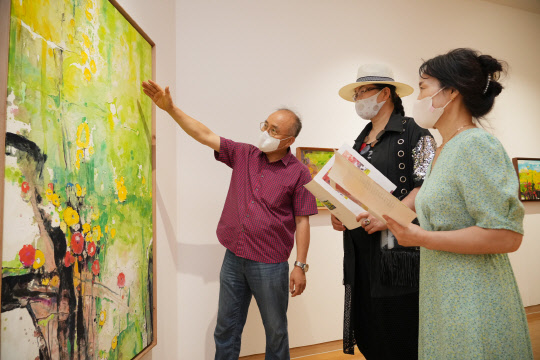 강해중 작가(왼쪽 첫번째)가 BNK경남은행갤러리를 찾은 지역민들에게 작품을 안내하고 있다. BNK경남은행 제공
