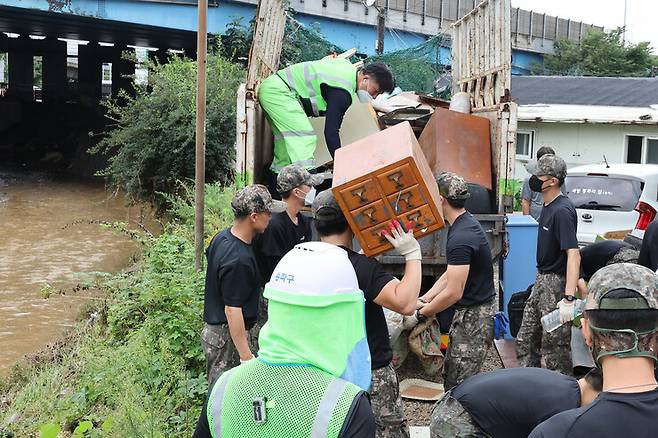 11일 오전 대규모 수해를 입은 서울 송파구 화훼마을에서 육군 52사단과 56사단 장병들이 환경미화원들과 함께 비에 젖어 못 쓰게 된 물건들을 정리하고 있다. 연합뉴스