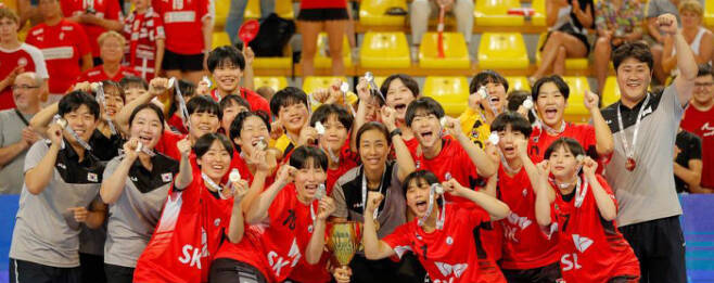 한국 여자핸드볼 청소년 대표팀 선수들과 코치진이 11일 북마케도니아 스코페에서 열린 2022 세계여자청소년 핸드볼선수권대회 결승에서 덴마크를 꺾고 우승한 뒤 금메달을 들어보이며 활짝 웃고 있다. 국제핸드볼연맹 제공