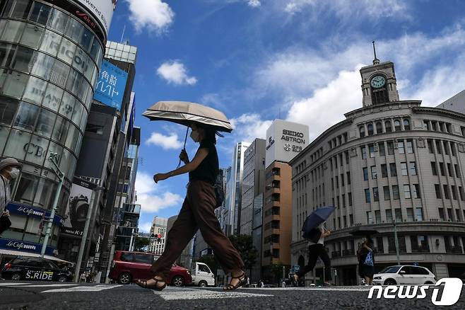 일본 도쿄 긴자 시내에 한 보행자가 무더위를 피하기 위해 양산을 들고 횡단보도를 건너고 있다.  2022.08.11 ⓒ AFP=뉴스1 ⓒ News1 정윤미 기자