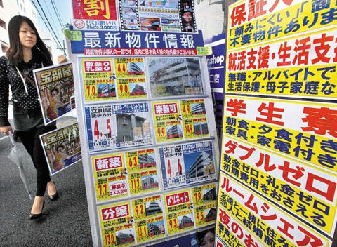 부동산 중개업소의 주택 임대·매매 광고가 내걸린 일본 도쿄 거리를 한 시민이 지나가고 있다. /블룸버그 통신