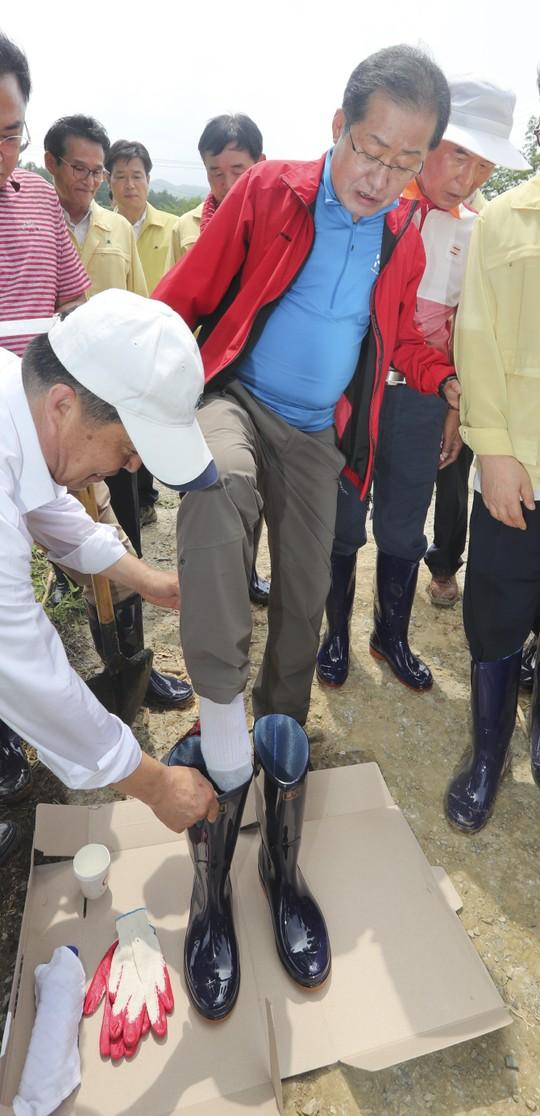 홍준표 대구시장이 2017년 수해 복구 봉사활동을 나섰다가 관계자 도움을 받아 장화 신는 장면이 촬영돼 비판을 받았다. 연합뉴스