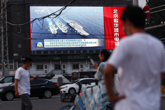 베이징의 한 거리에서 주민들이 인민해방군 해군의 훈련 장면 뉴스를 보고 있다. [사진=로이터,연합뉴스]
