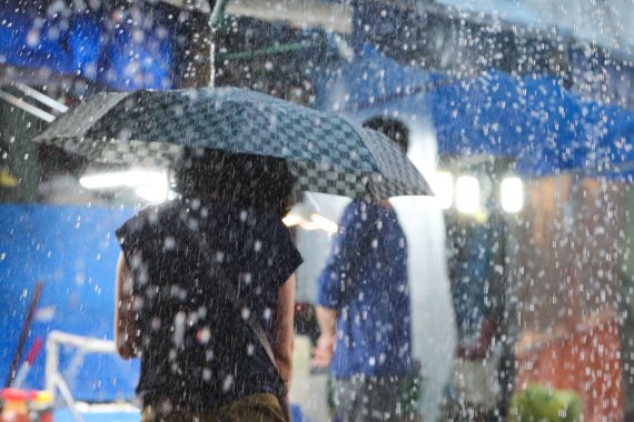 지난 8일 서울 강동구 둔촌역 전통시장에서 시민들이 우산을 쓰고 이동하고 있다. 사진=뉴시스