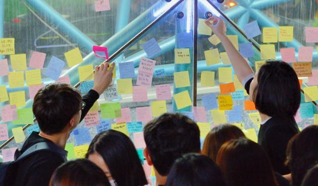 강남역 살인사건 1주기인 2017년 5월 17일 추모 문화제에 참석한 남녀 시민들이 강남역 10번 출구에 추모글을 쓴 포스트잇을 붙이고 있다. 왕태석 기자
