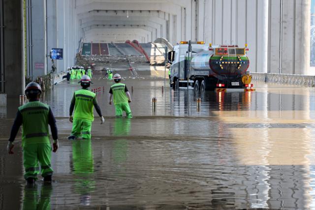 12일 오후 폭우로 인한 한강 수위 상승으로 닷새 동안 양방향이 통제된 서울 잠수교에서 관계자들이 통행 재개를 위한 복구 작업을 하고 있다. 뉴스1