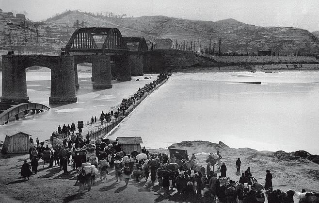 한국전쟁 때 파괴된 한강 인도교(현 한강대교) 아래 임시 다리를 건너는 피란민들. 1951년 [국가기록원 제공]