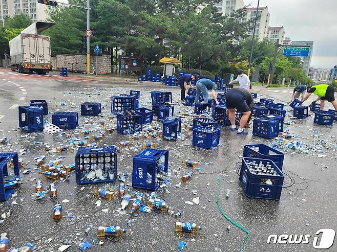 지난 6월 29일 춘천시 퇴계동의 한 사거리에서 5톤 트럭에 실려있던 맥주병 2000여병이 바닥으로 떨어지는 사고가 발생, 길을 가던 시민들이 청소를 돕고 있다.(독자 제공)