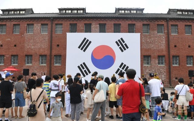 광복절 77주년을 하루 앞둔 14일 시민들이 서울 서대문형무소역사관 앞 대형 태극기 앞에서 기념촬영을 하고 있다.