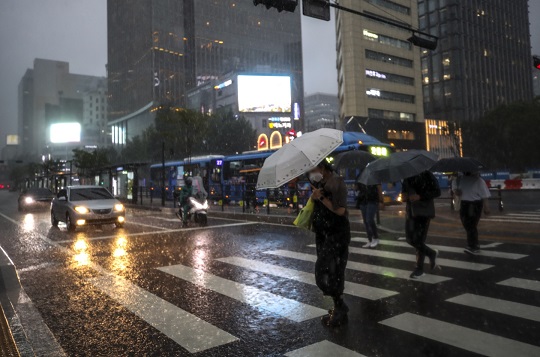 지난 6월 서울 종로구 광화문광장 인근 폭우에 시민들이 우산을 쓴 채 이동하고 있다. 사진=뉴시스