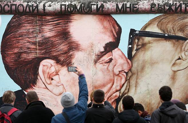 2014년 베를린 장벽 붕괴 25주년 당시 드미트리 브루벨이 그린 벽화 ‘형제의 키스’ 앞에 사람들이 모여있다. /게티이미지코리아