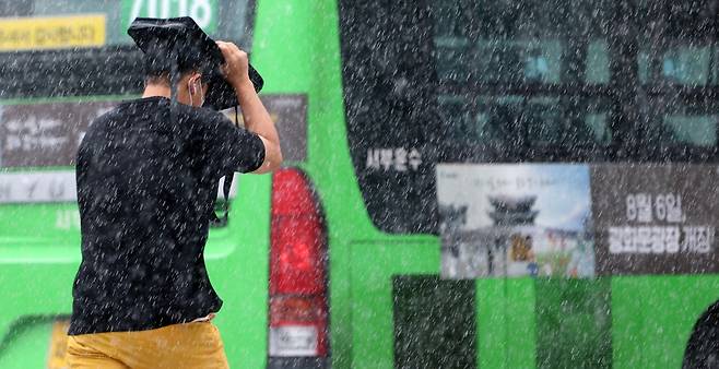 소나기가 내린 6일 서울 종로구 광화문 앞 삼거리도로에서 한 시민이 가방으로 비를 피하며 발걸음을 재촉하고 있다./뉴스1