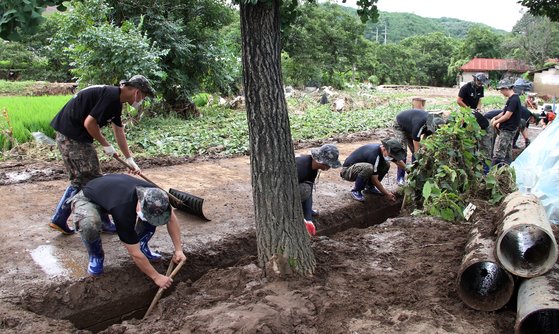 15일 충남 청양군 남양면 온직리에서 육군 제32사단 장병들이 전날 새벽 폭우로 쌓인 배수로 흙을 삽으로 퍼내고 있다. 연합뉴스