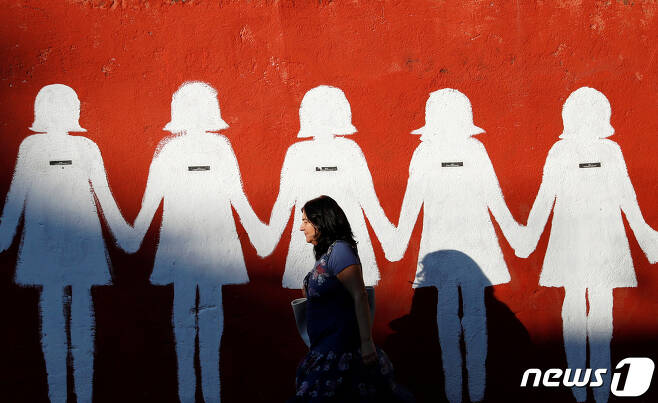 2020년 6월25일(현지시간) 이탈리아 로마에서 한 여성이 예술가 엘리사 카라촐로가 만든 페미사이드(Femicide·여성이라는 이유로 살해당하는 것) 희생자들을 기리는 벽화를 지나가고 있다. 20.06.25 ⓒ 로이터=뉴스1 ⓒ News1 김예슬 기자