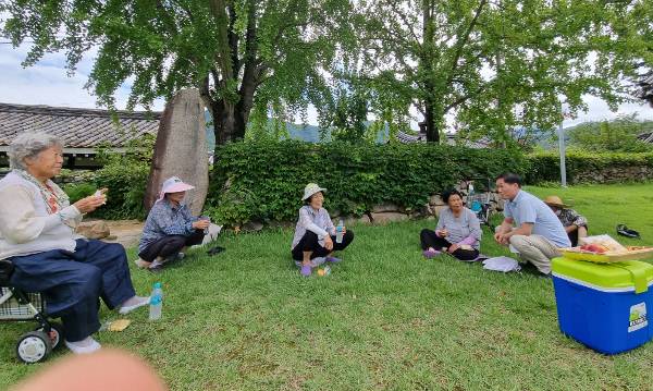 배용한(군위 대율교회·오른쪽) 목사가 지난 5일 경북 군위군 부계면의 한 공터에서 잡초제거 작업을 마친 뒤 쉬고 있는 동네 어르신들에게 생수와 카스텔라를 나눠준 뒤 담소를 나누고 있다.