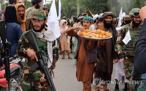 아프간 칸다하르에서 탈레반 대원에게 과자 등을 주는 지지자. [UPI 연합뉴스 자료사진. 재판매 및 DB 금지]