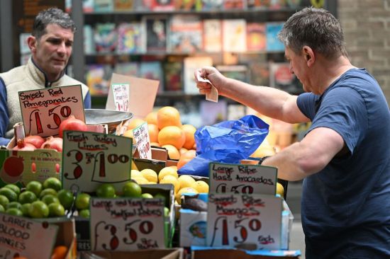 영국 런던의 한 청과물상에서 한 고객이 과일과 채소 대금으로 10파운드 지폐를 건네고 있다. [이미지출처=연합뉴스]