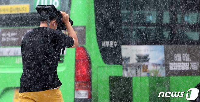 소나기가 내리는 서울 종로구 광화문 앞 삼거리도로에서 한 시민이 가방으로 비를 피하며 발걸음을 재촉하고 있다. /사진=뉴스1