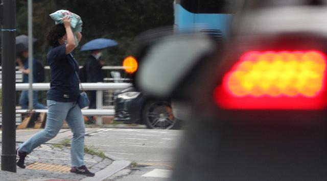 소나기가 내린 지난 17일 오후 서울 도심에서 한 시민이 가방으로 머리를 가린 채 걷고 있다. 뉴시스