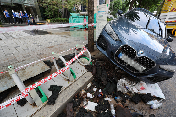 10일 서울 강남역 인근 한 빌딩에서 배수 작업이 진행되고 있는 가운데 침수된 차가 방치되어 있다. 연합뉴스