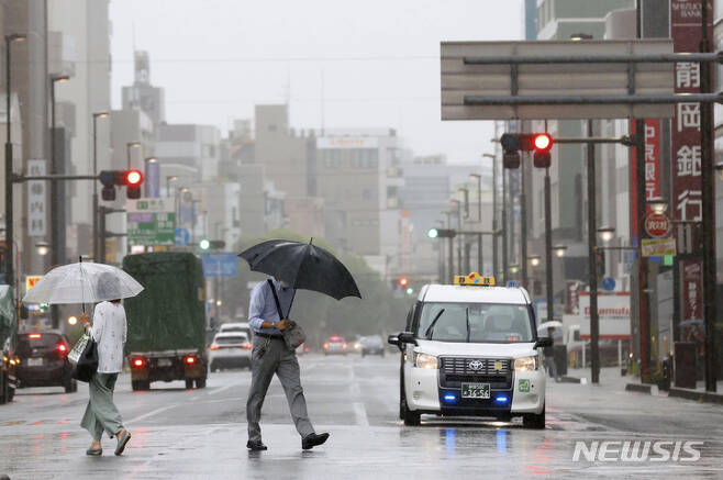 [시즈오카=AP/뉴시스]지난 13일 일본 시즈오카에 비가 몰아치면서 시민들이 우산을 꼭 잡고 길을 건너고 있다.  이날은 태풍 메아리가 도쿄를 향해 하며 폭우가 쏟아졌다. 2022.08.18.