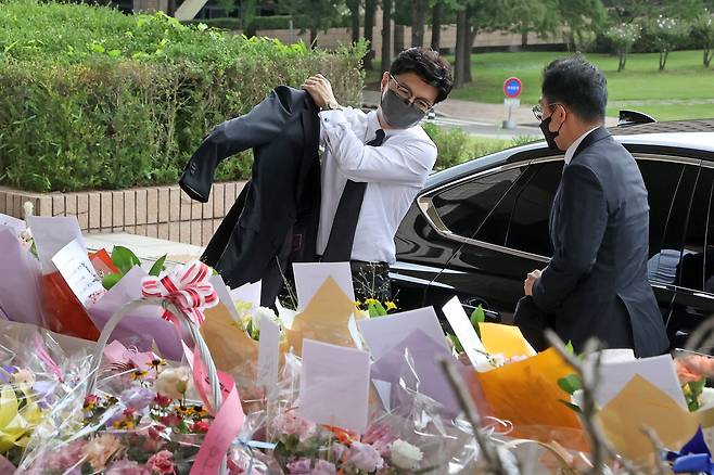 재킷을 입으며 꽃을 보는 한동훈 장관이 미소를 짓고 있다. 뉴스1