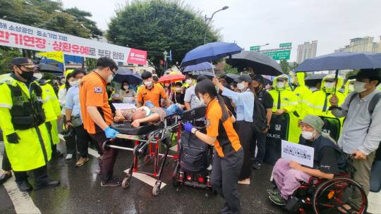 전국장애인차별철폐연대 회원이 29일 오전 서울 용산구 대통령 집무실 행진을 하다 휠체어에서 떨어져 119가 출동해 호송하고 있다. 김보름 기자