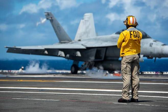 미 해군 핵항모 로널드 레이건호 승조원이 비행갑판에서 이륙 대기중인 F/A-18E/F 전투기를 바라보고 있다. 미 해군 제공
