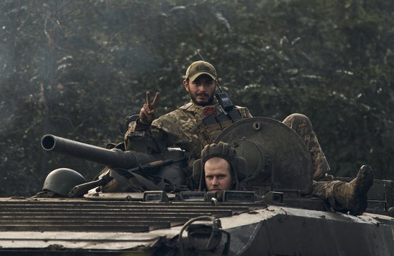 러시아가 점령했던 우크라이나 북동부 하르키우 인근의 전략적 요충지인 이지움을 수복한 우크라이나 군인이 13일 BMP-2 보병전투차를 타고 승리의 V자를 보이고 있다. [AP=연합뉴스]