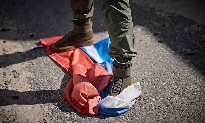 지난 19일(현지시간) 한 우크라이나군 병사가 최근 러시아군을 몰아내고 탈환한 하르키우 쿠피얀스크 지역에서 러시아 국기를 밟고 있다. 쿠피얀스크=AFP연합뉴스