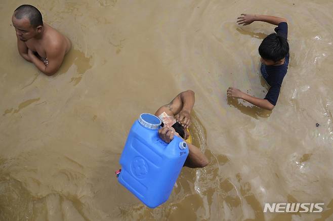 [불라칸=AP/뉴시스] 26일(현지시간) 필리핀 불라칸주 산미구엘에서 주민들이 마실 물을 사러 가기 위해 태풍 '노루'로 침수된 도로를 지나고 있다. 2022.09.27.