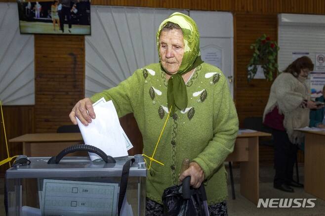 [루한스크=AP/뉴시스]러시아군이 점령하고 있는 우크라이나 동부 루한스크 지역의 한 노인이 러시아와 합병 주민투표에 참여해 투표지를 투표함에 넣고 있다. 2022.9.26.