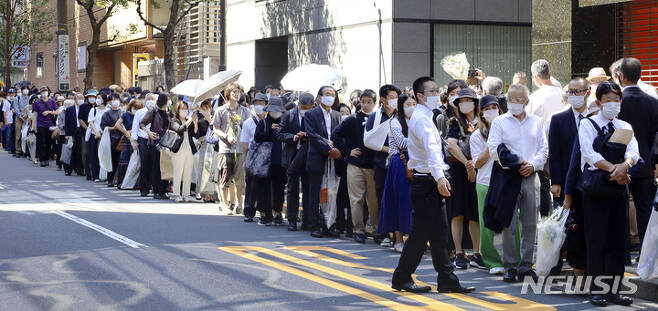 [도쿄=AP/뉴시스] 27일 일본 도쿄에서 시민들이 아베 신조 전 총리의 국장이 열리는 무도관 바깥 자리에서 헌화하기 위해 긴 줄을 서 있다. 2022.09.27.