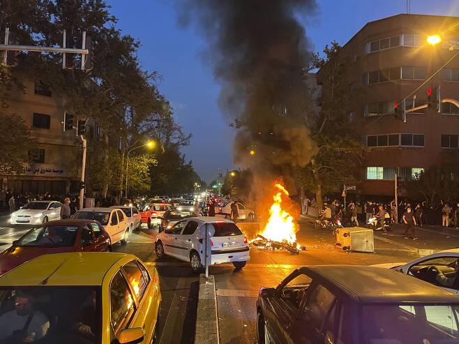 19일(현지 시각) 이란 수도 테헤란 시내에서 '히잡 미착용 20대 여성 의문사 사건'에 항의하는 시위가 벌어진 가운데 경찰 오토바이가 불타고 있다.